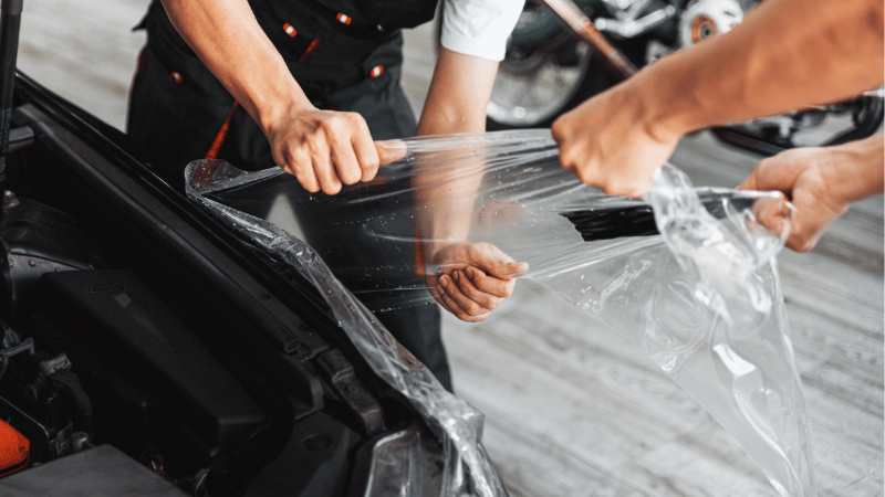Two men are removing the car wrap without damaging the paint.