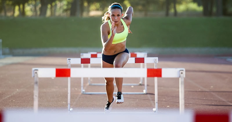 An athletic woman jumping over hurdles, representing the obstacles we face in daily life.