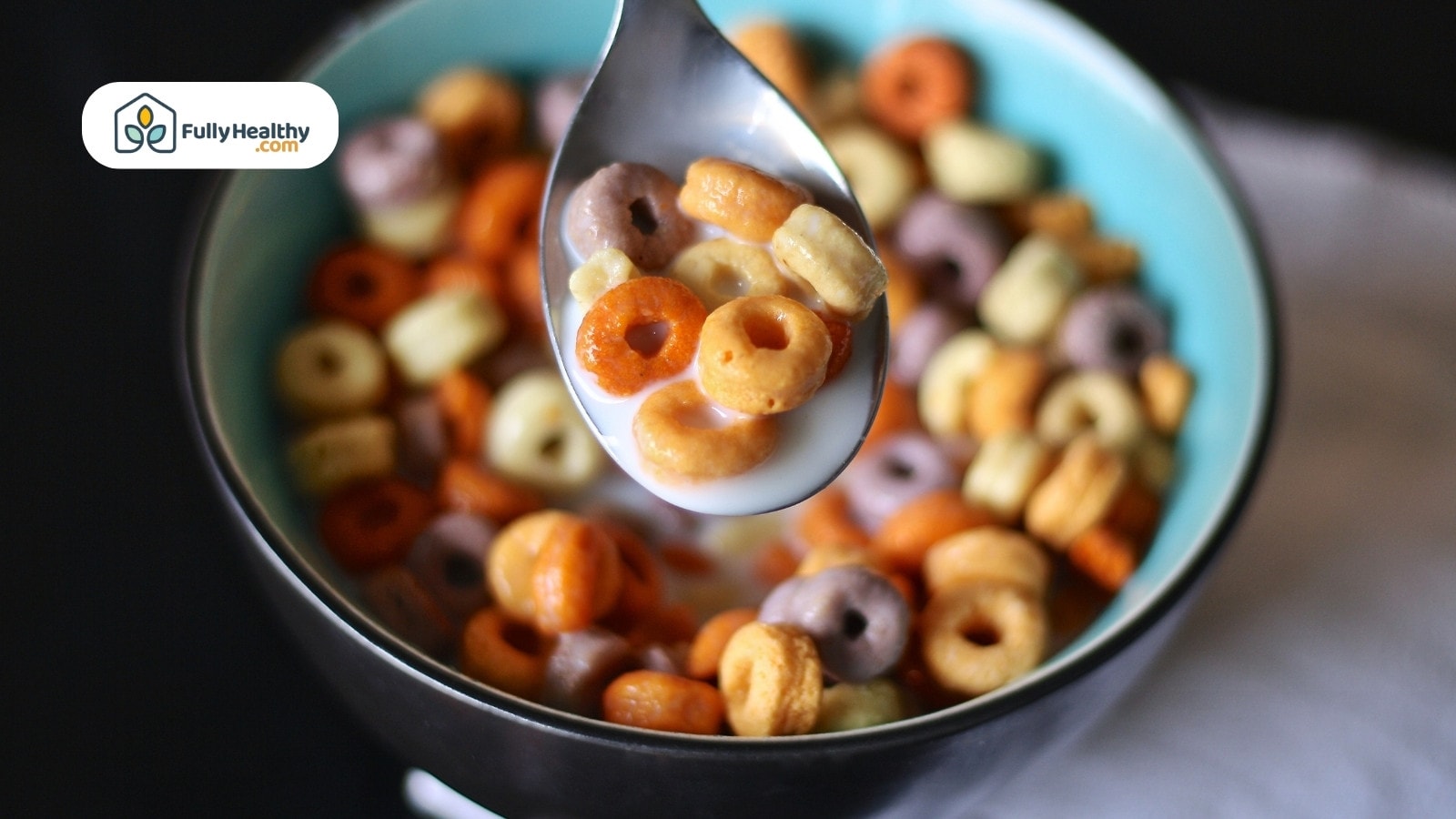 Colorful cereal loops with milk in spoon over blue bowl