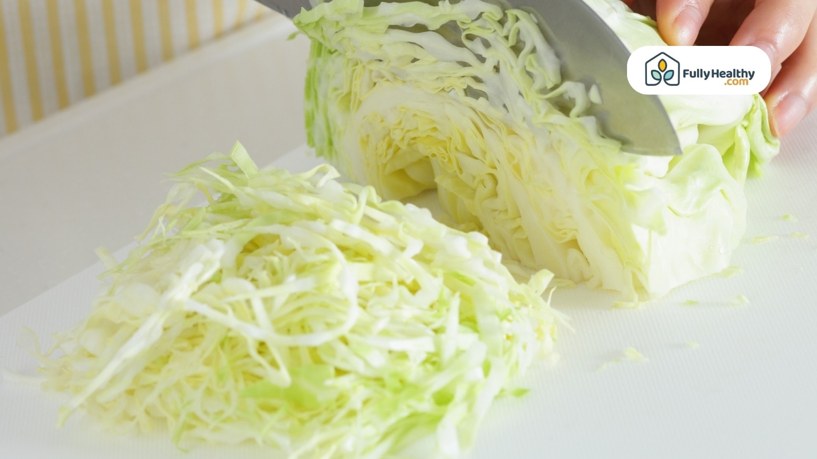 Chopped cabbage being sliced with knife on white cutting board