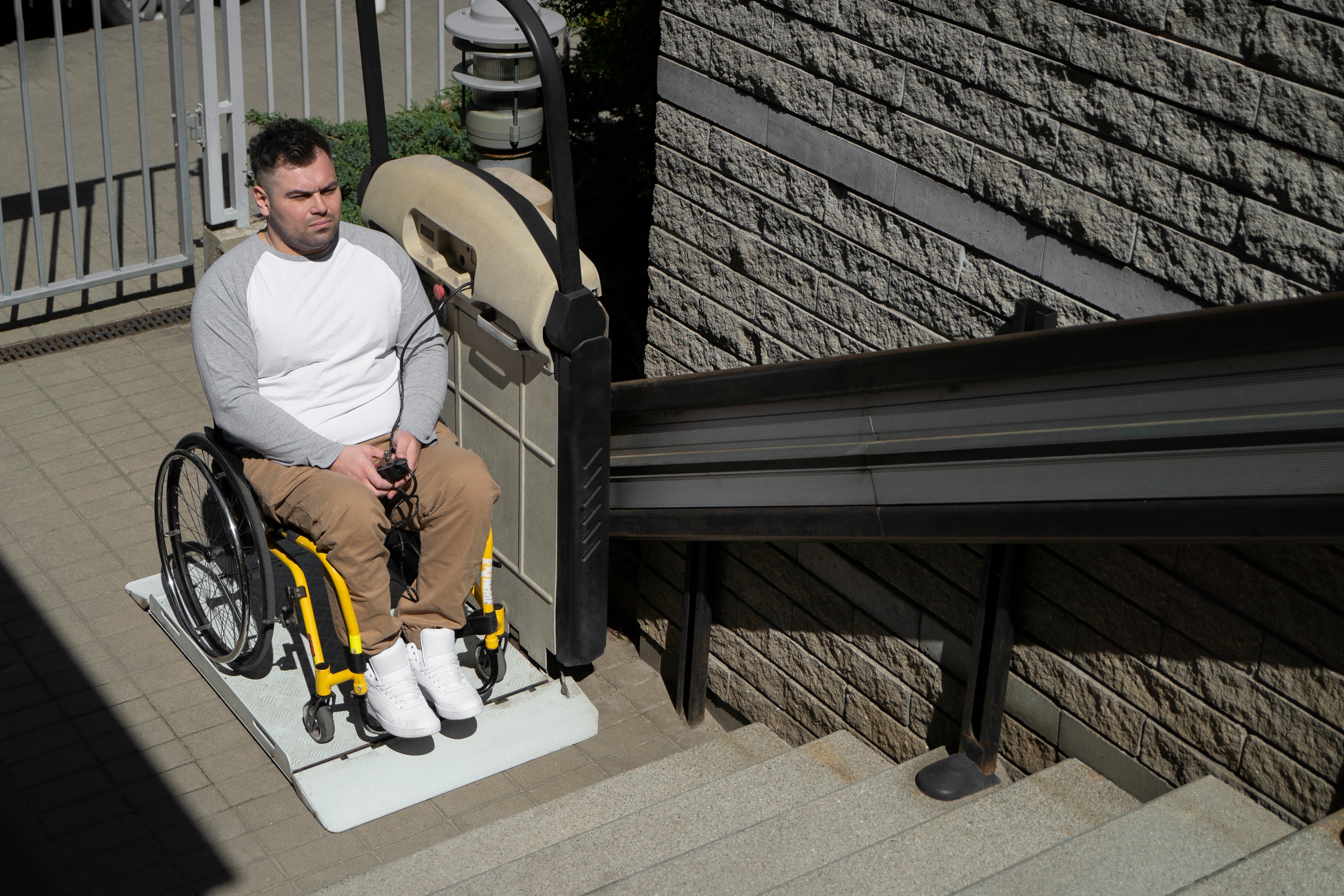 A stair stretcher helping a wheelchair user ascend stairs outdoors.