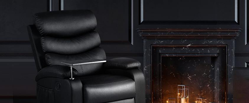 The Artiss Black PU Leather Recliner with tray table, set in front of a black wall and black marble fireplace.