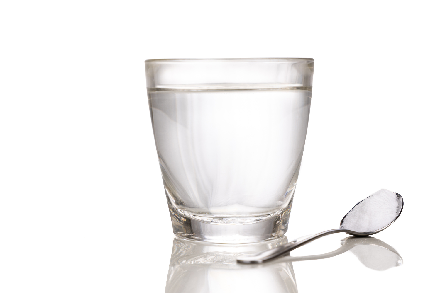 Glass of water with a spoon of white powder.