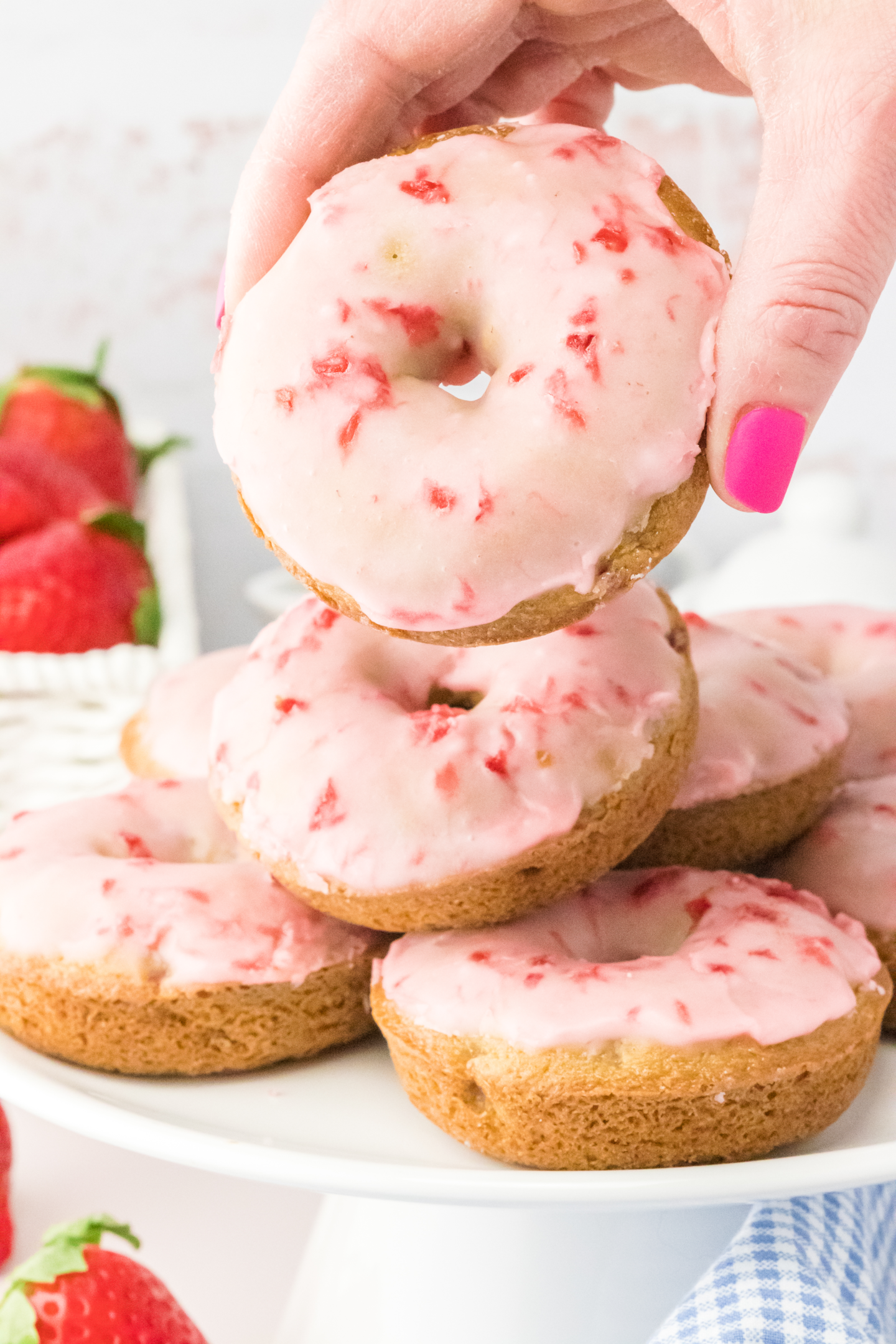 hand holding a strawberry donut with a strawberry glaze