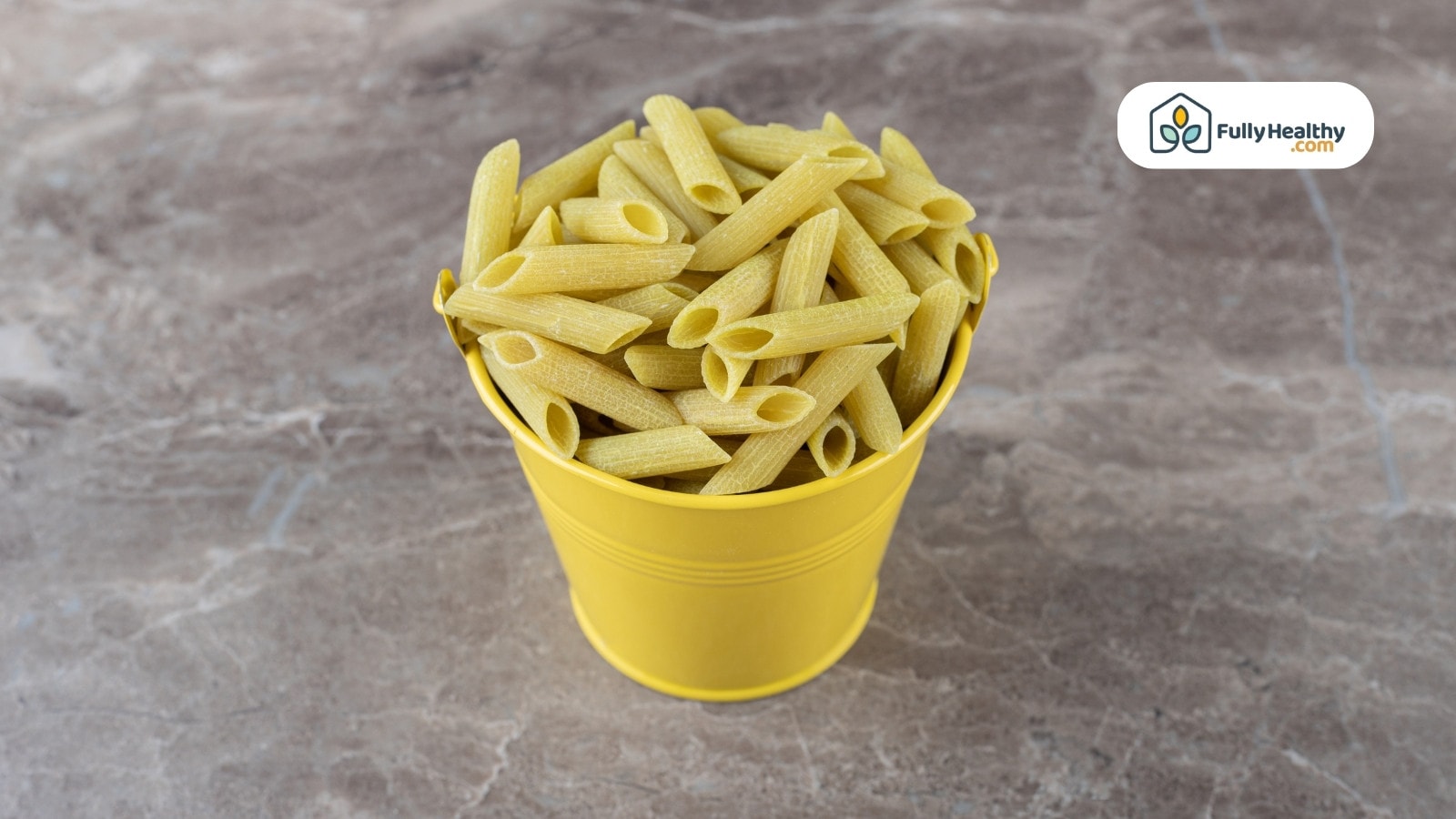 Uncooked penne pasta piled in a small bright yellow bucket