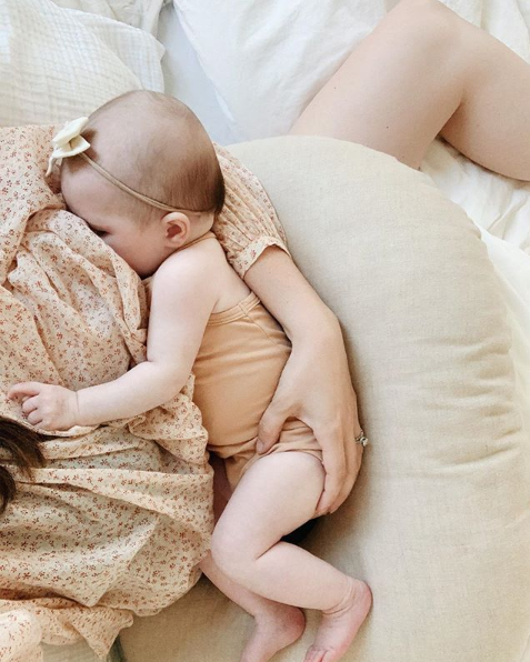 Newborn baby girl breastfeeding on a nursing pillow