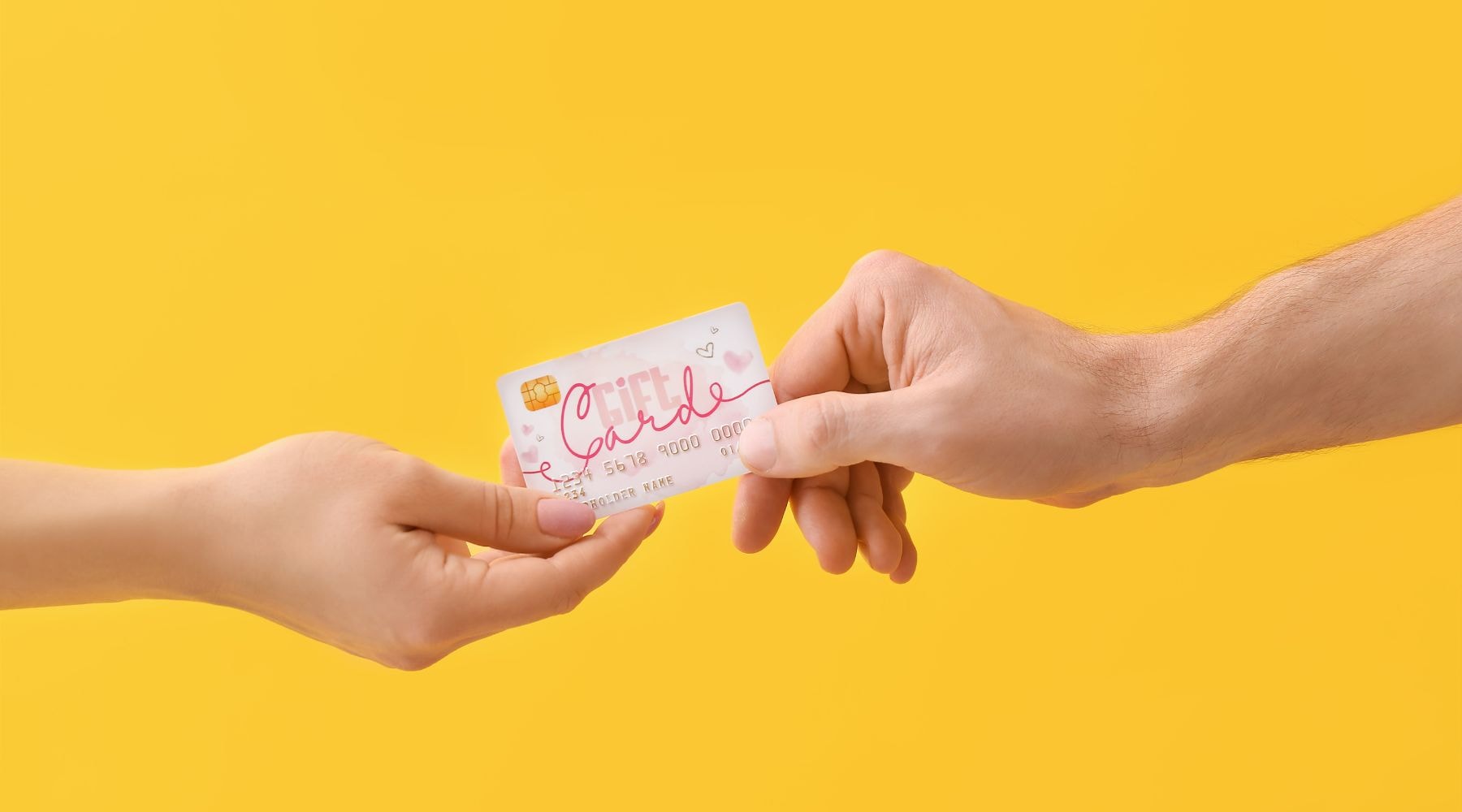 Two hands exchanging a gift card against a bright yellow background.