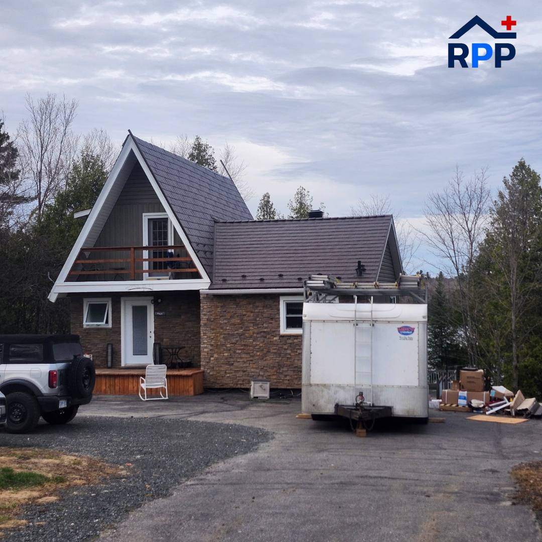 A residential house with a trailer parked in the driveway, showcasing the newly installed metal roof.
