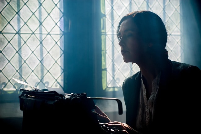 A woman typing on an antique typewriter.