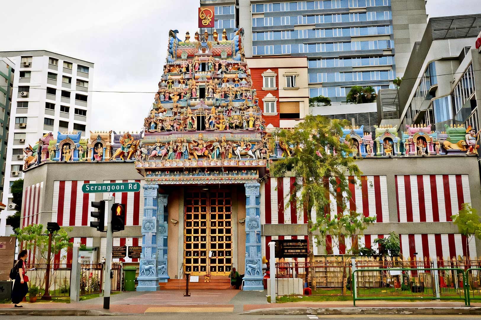 The ornate entrance of Sri Veeramakaliamman Temple featuring a colorful, intricately carved gopuram with numerous Hindu deities and figures above the main doorway.