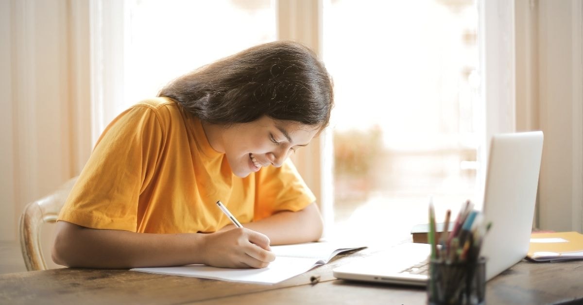 A woman smiling while filling out an empty W-9 form on her desk.