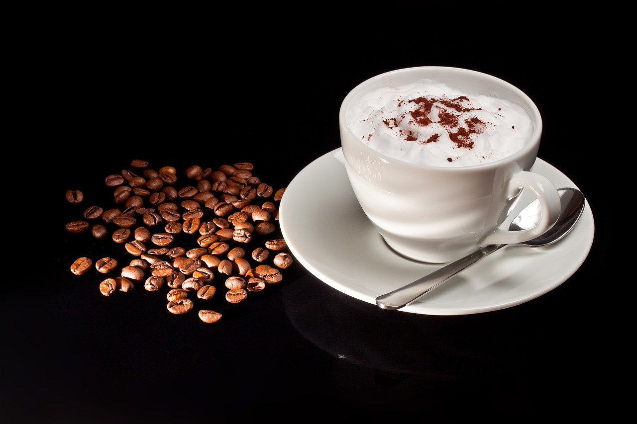 cup of espresso on saucer with spoon with a coffee bean next to it