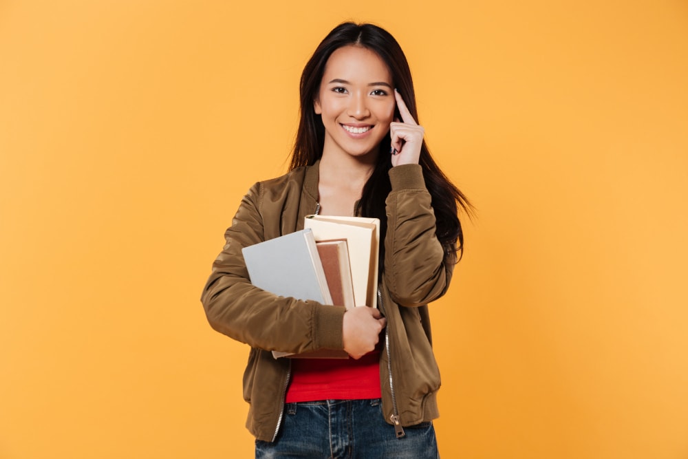 asian woman bringing books with a wide grin