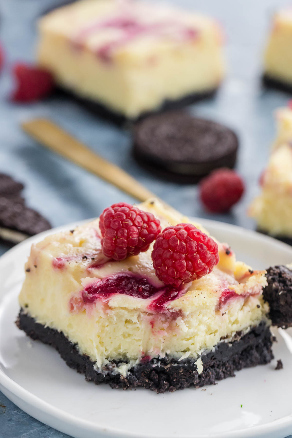white chocolate raspberry cheesecake bar on a plate with a fork