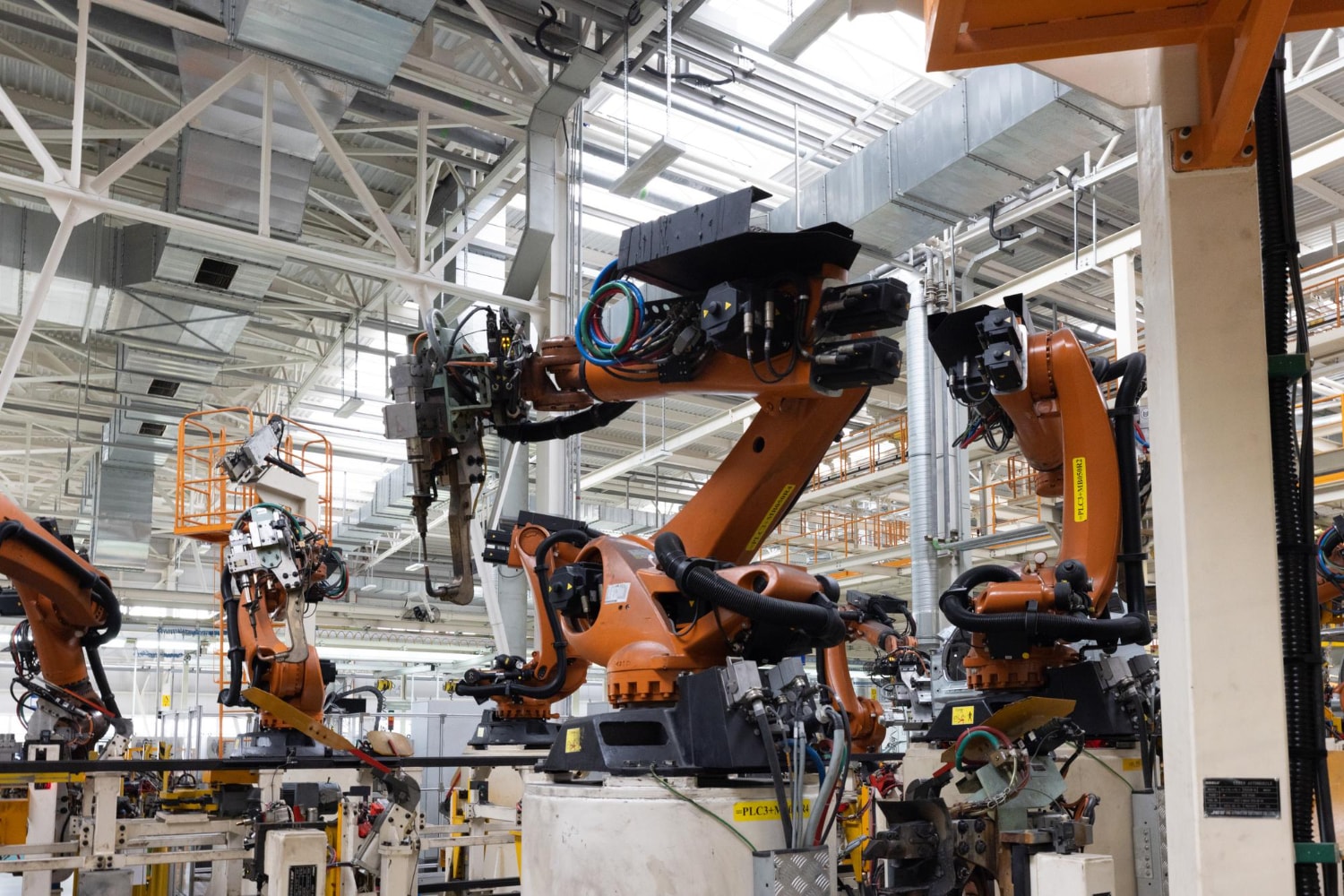 Multiple robotic arms operate in a fully automated factory equipped with high-tech machinery. UCaaS delivers cloud-based communication infrastructure that integrates with IoT systems, providing unified communications benefits such as predictive maintenance and remote monitoring through cloud telephony.
