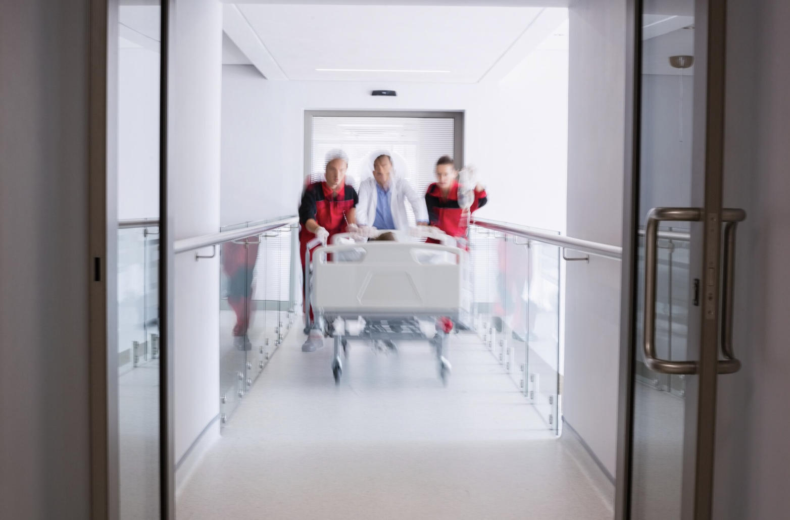 Doctors pushing emergency stretcher bed in corridor
