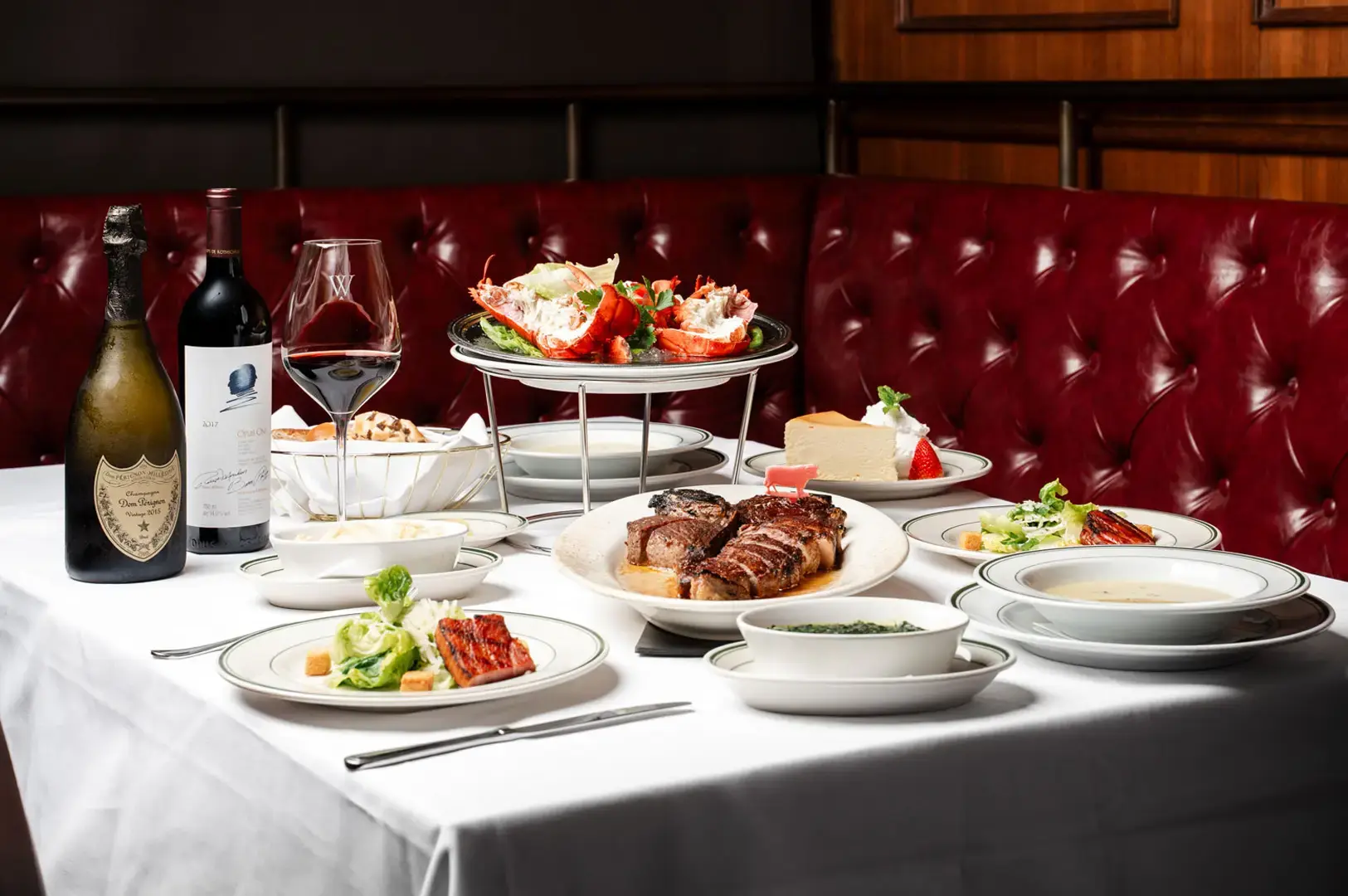 Wolfgang's Steakhouse Singapore steakhouse dining table with grilled steak, lobster, wine and classic sides