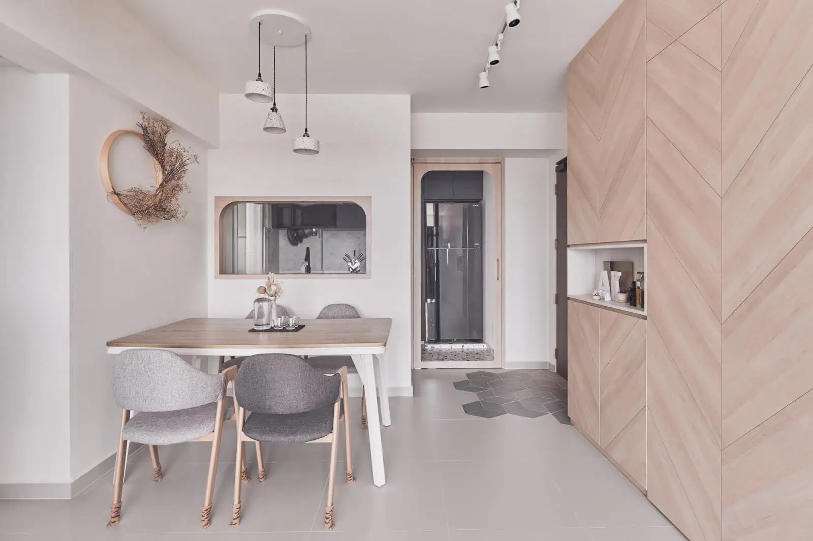 Scandinavian homes interior design – dining nook with light-wood herringbone cabinet, grey upholstered chairs, and pendant trio.