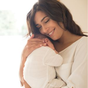 mother smiling and holding her newborn baby