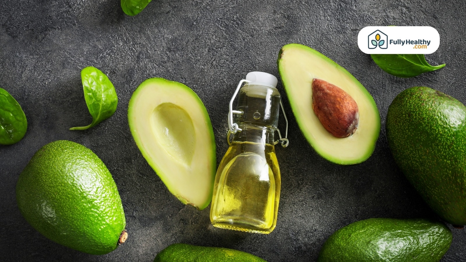 Bottle of avocado oil surrounded by halved avocados and spinach leaves