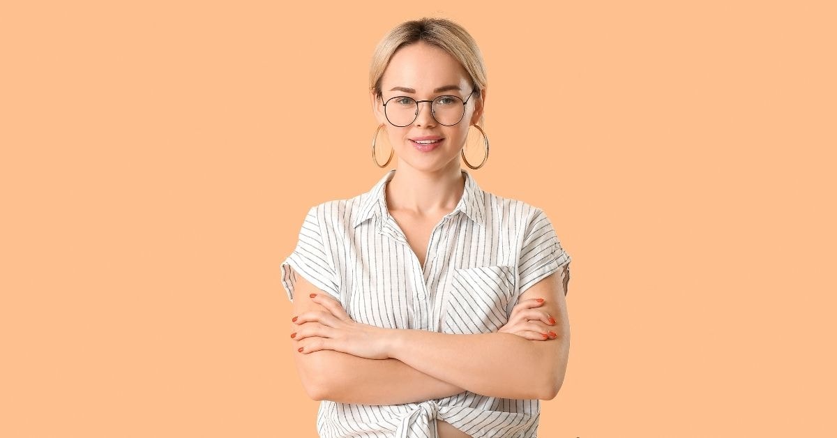 Smiling woman with glasses and a striped shirt crosses her arms, representing confidence in the surcharge news.