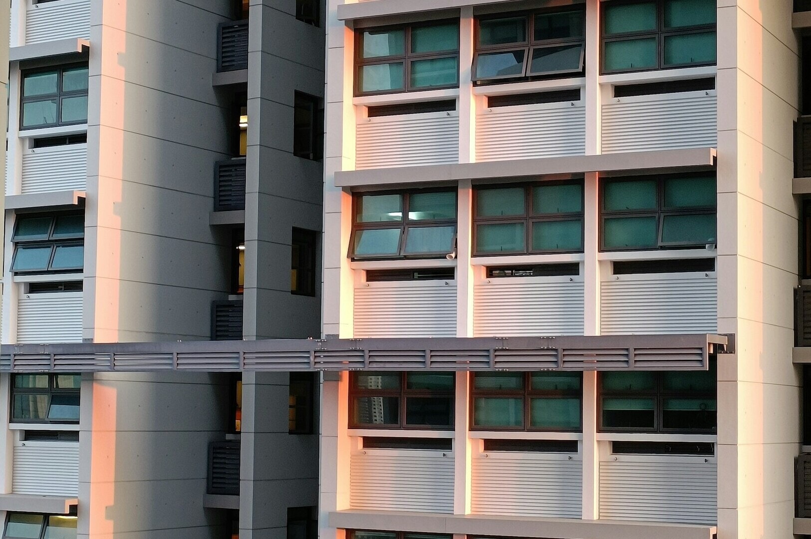 A university building in Singapore featuring numerous windows and a prominent clock on its facade.