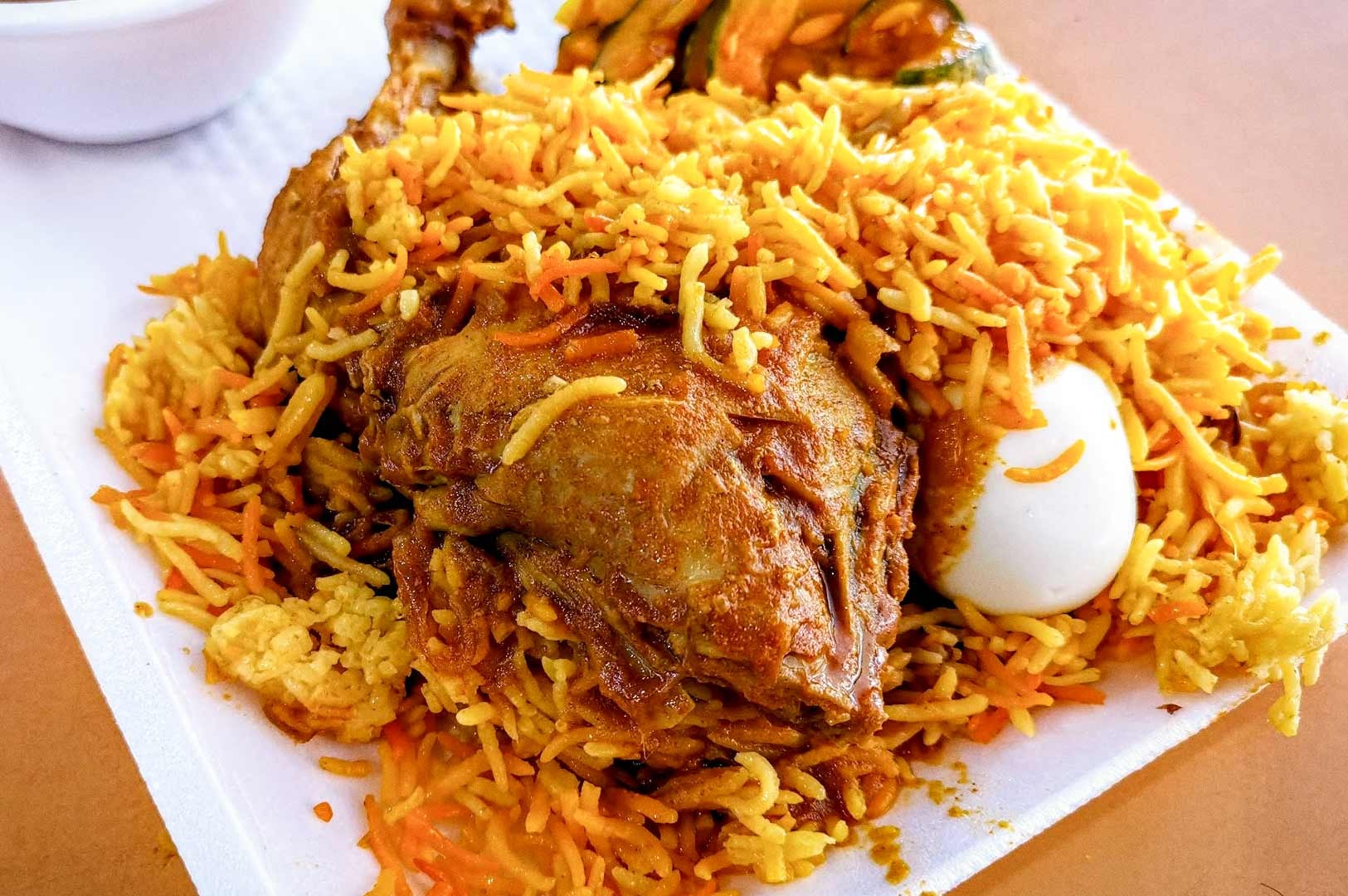 A plate of chicken biryani topped with spiced rice, a cooked chicken leg, and a hard‑boiled egg.