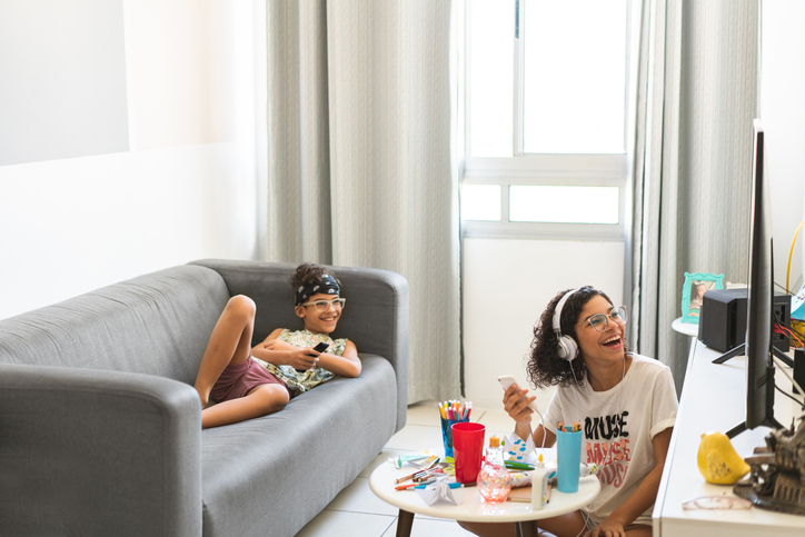 Happy young mom and daughter watching television. 