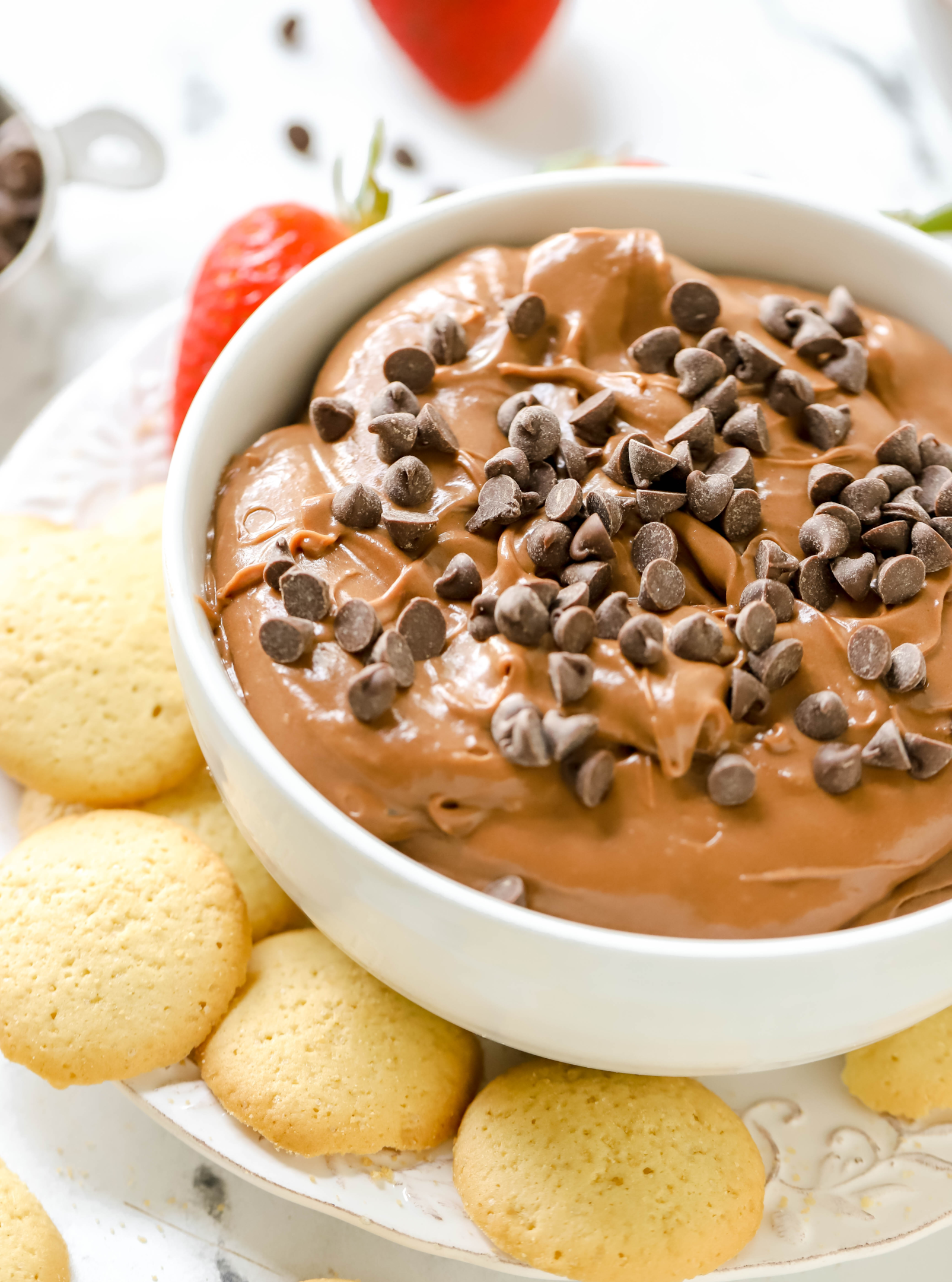 bowl of brownie batter dip, topped with mini chocolate chips, on a plate with Nilla wafers