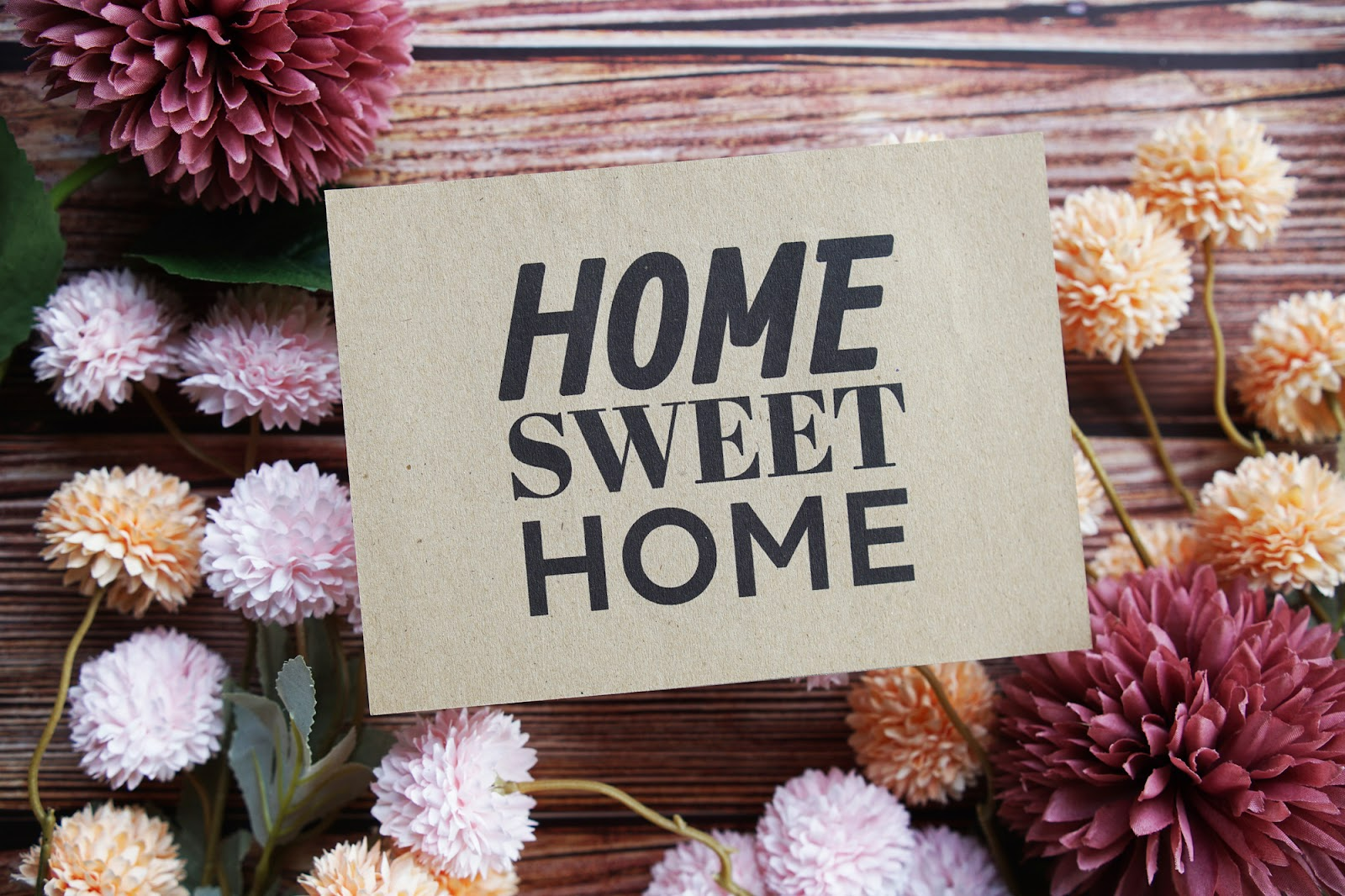 Flowers surround a sign that reads “home sweet home.”