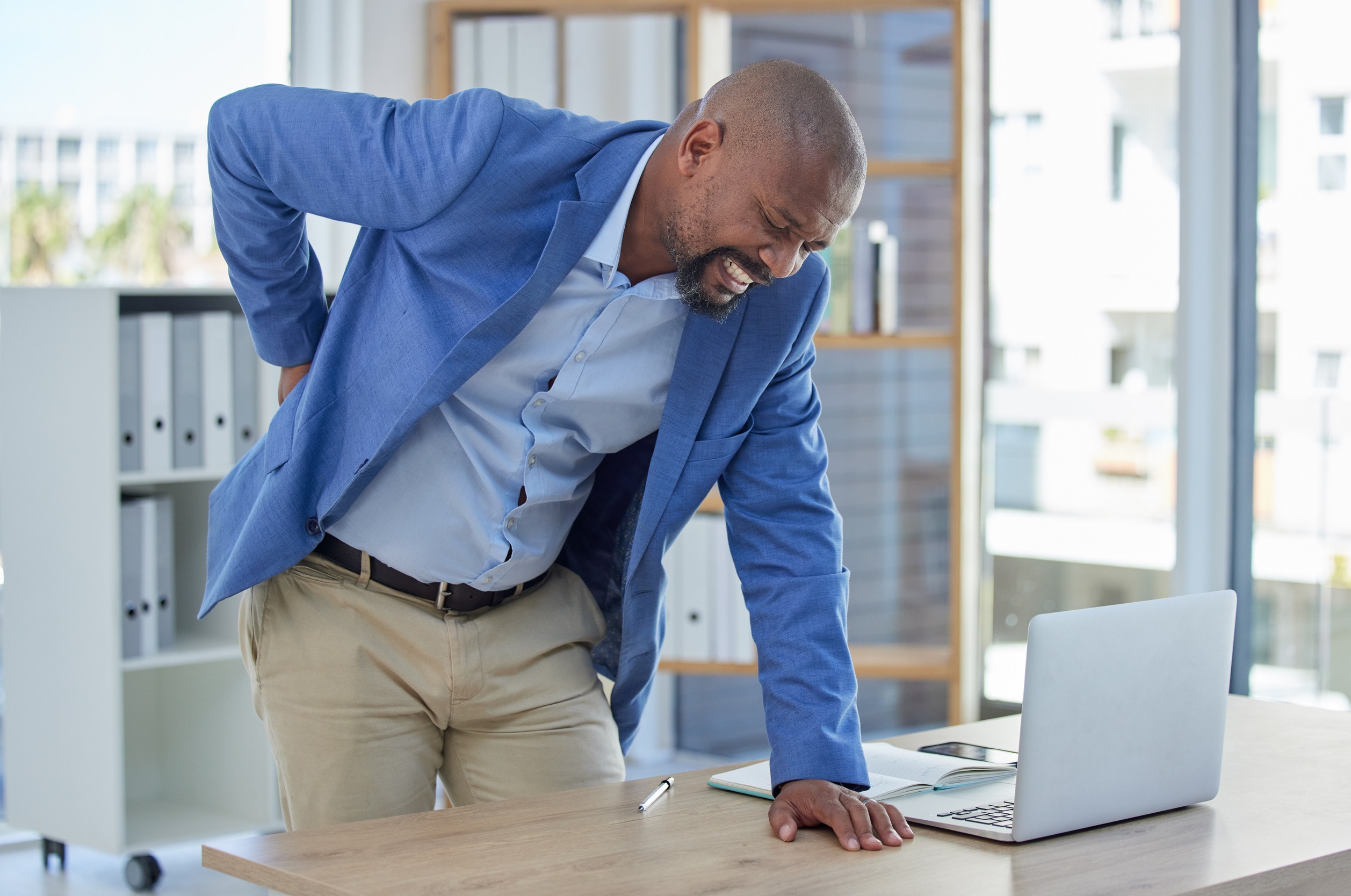 A worker in a blue blazer makes an office accident compensation claim after suffering a back injury 