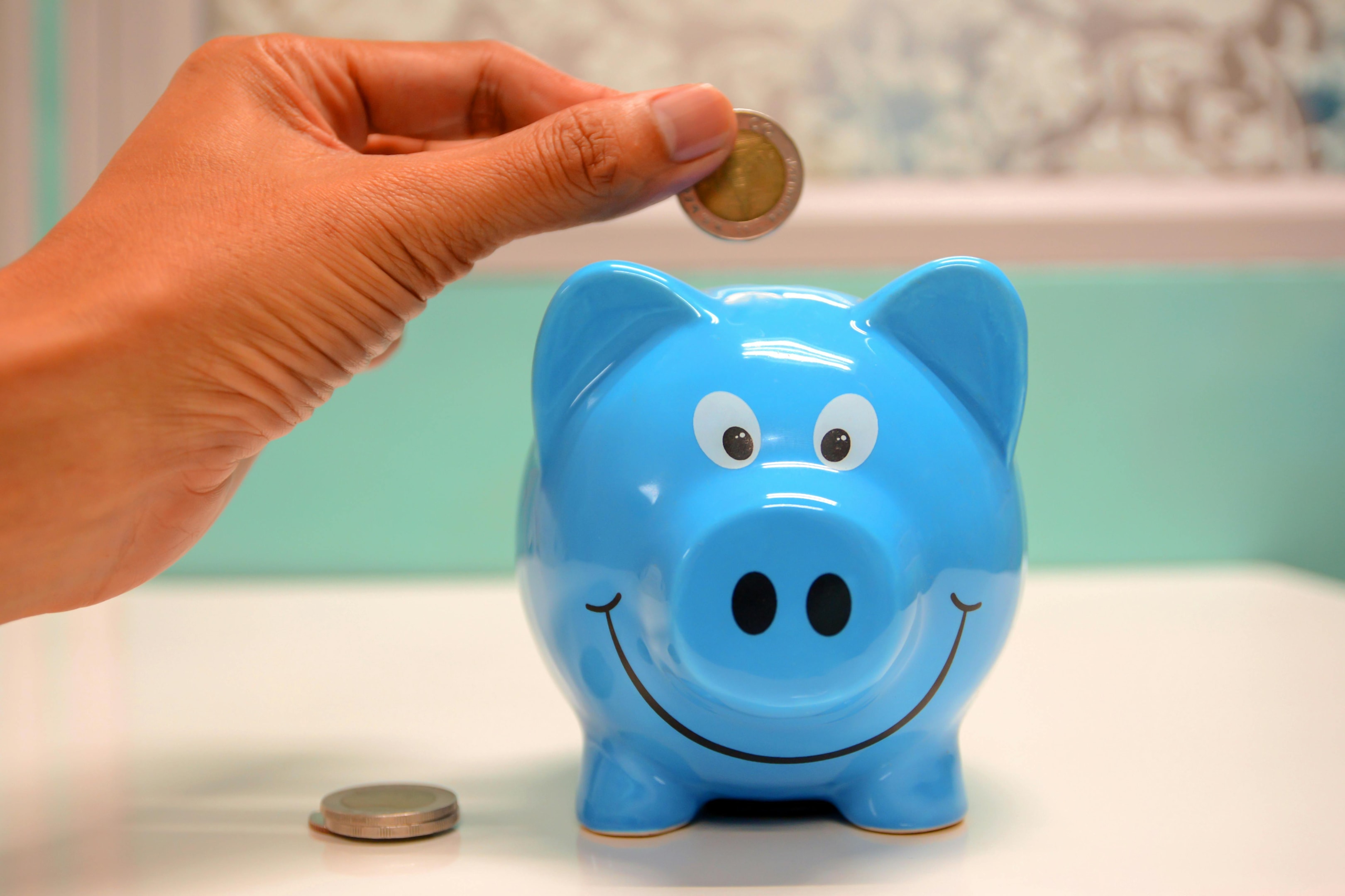 Someone putting coins into piggy bank. 