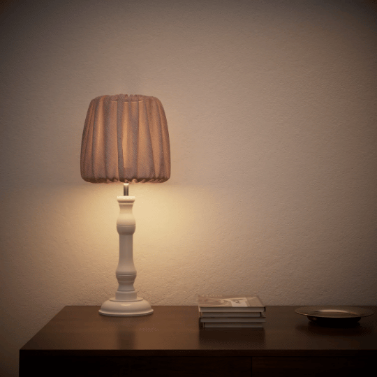 Soft fabric table lamp casting a warm glow on a wooden surface in a calm minimalist interior.