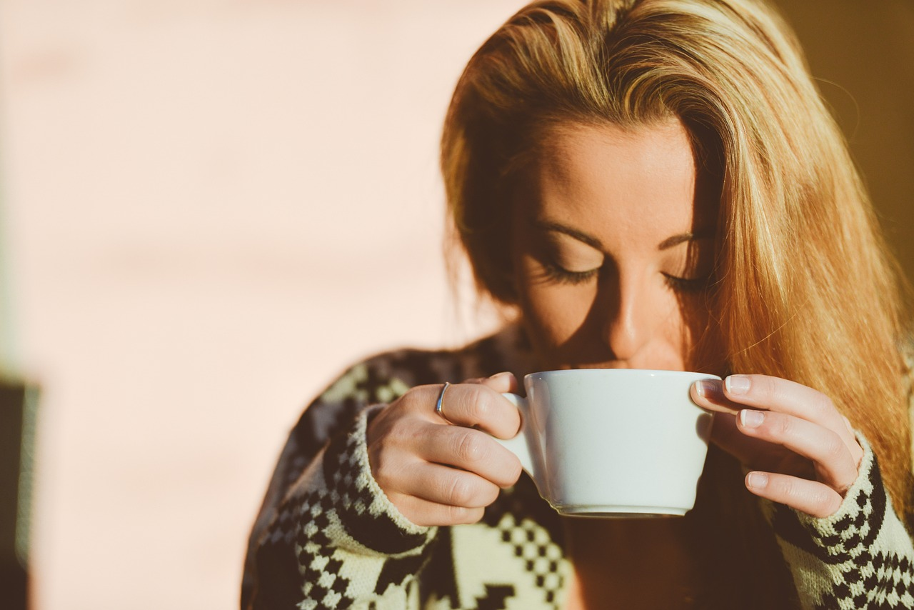 An image of a young woman drinking a cup of tea.