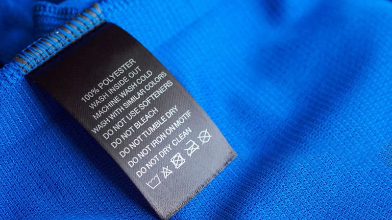 Black laundry care washing instructions clothes label on blue jersey polyester sport shirt Polyester Stock Photo