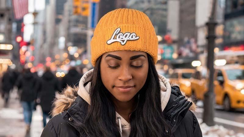 a woman standing on the sidewalk with a custom yellow beanie