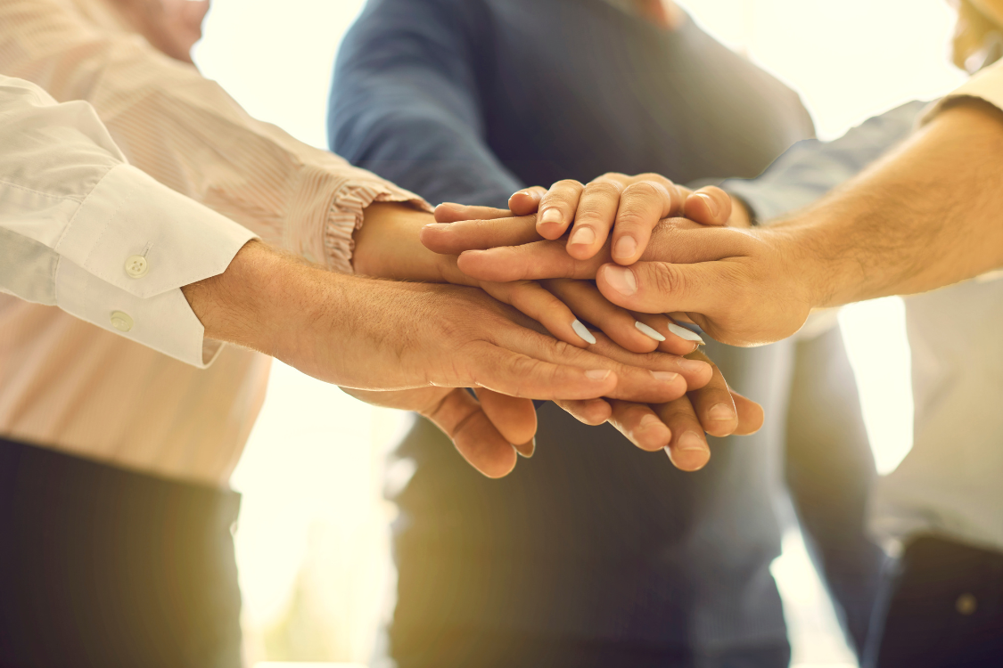 Multiple hands stacked together symbolizing teamwork and unity in a Filipino remote work culture