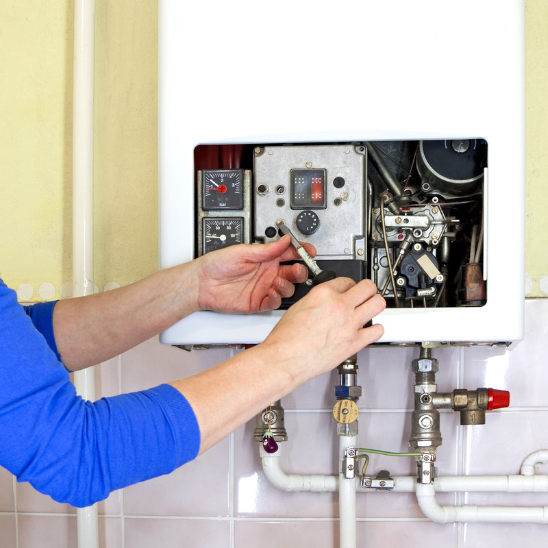 Techniker wartet eine Gas-Therme mit Werkzeugen.
