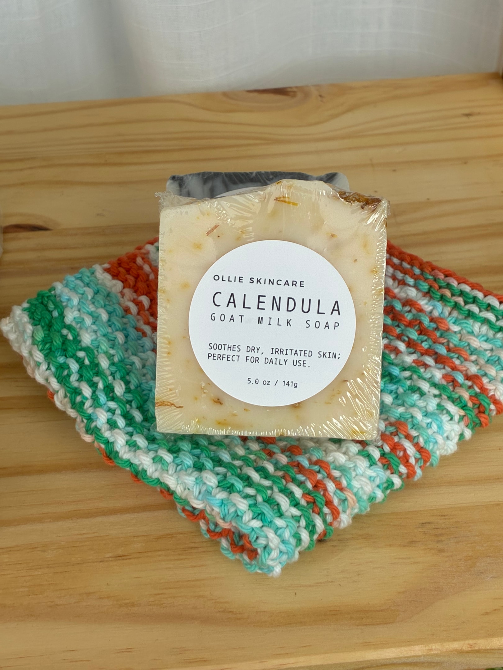 The image features a collection of artisan soap bars, including goat milk soap, elegantly arranged on a rustic wooden surface, illuminated by soft natural lighting. The soaps showcase various textures and colors, hinting at their natural ingredients like coconut oil and essential oils, creating a warm and inviting display.