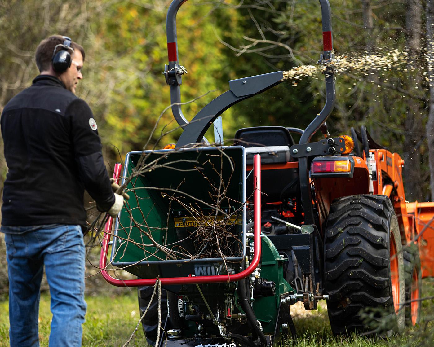 A man chipping twigs and branches in a Woodland Mills wood chipper.