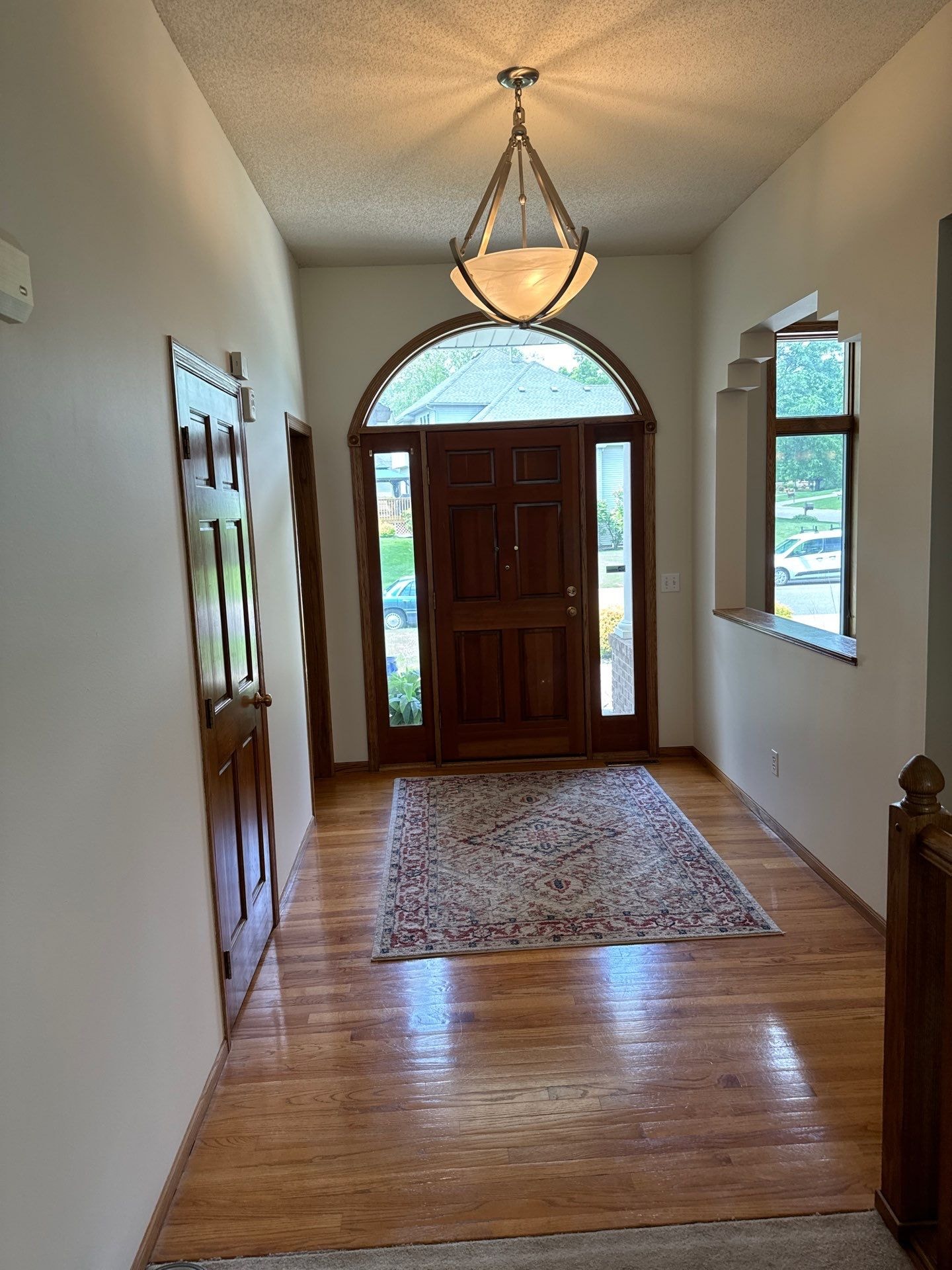 This inviting entryway features warm, neutral living room color ideas with light beige walls and rich hardwood floors