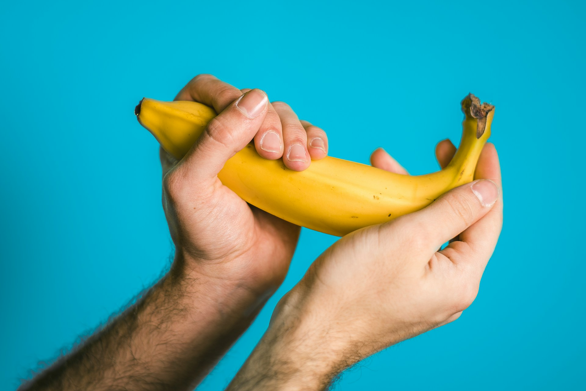 A man holding a banana to represent masturbating, which you can reduce the frequency of to increase semen production