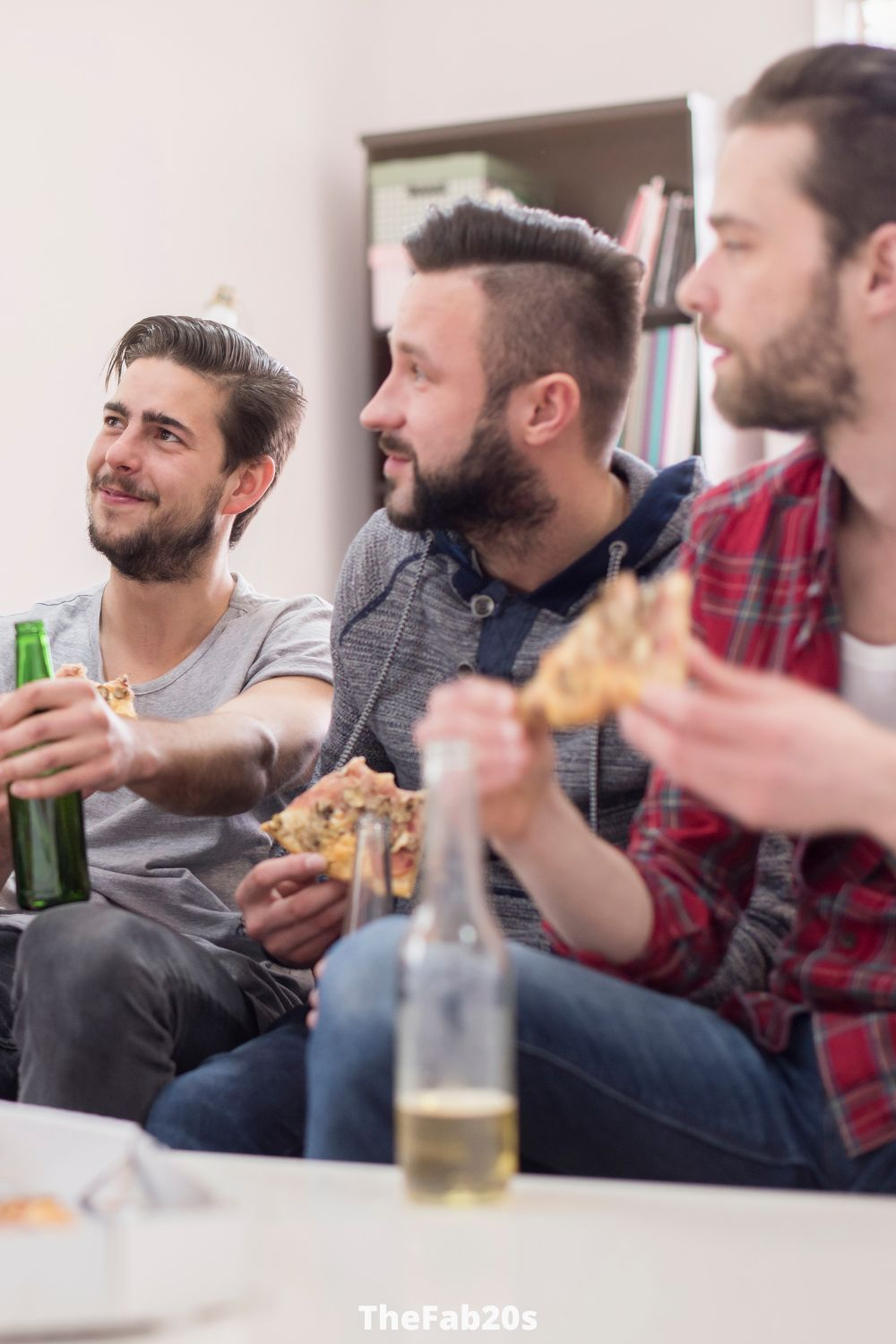 Groupd of guy friends sitting around a table, having pizza and beer