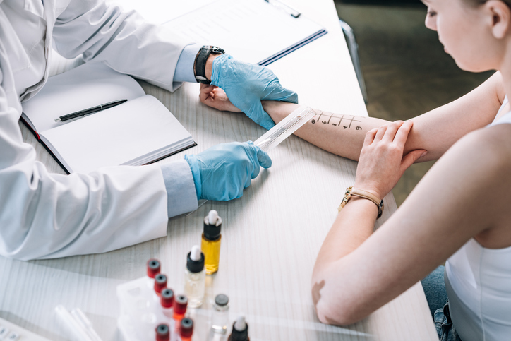 An image of a doctor performing allergy testing skin prick test on a young woman. 