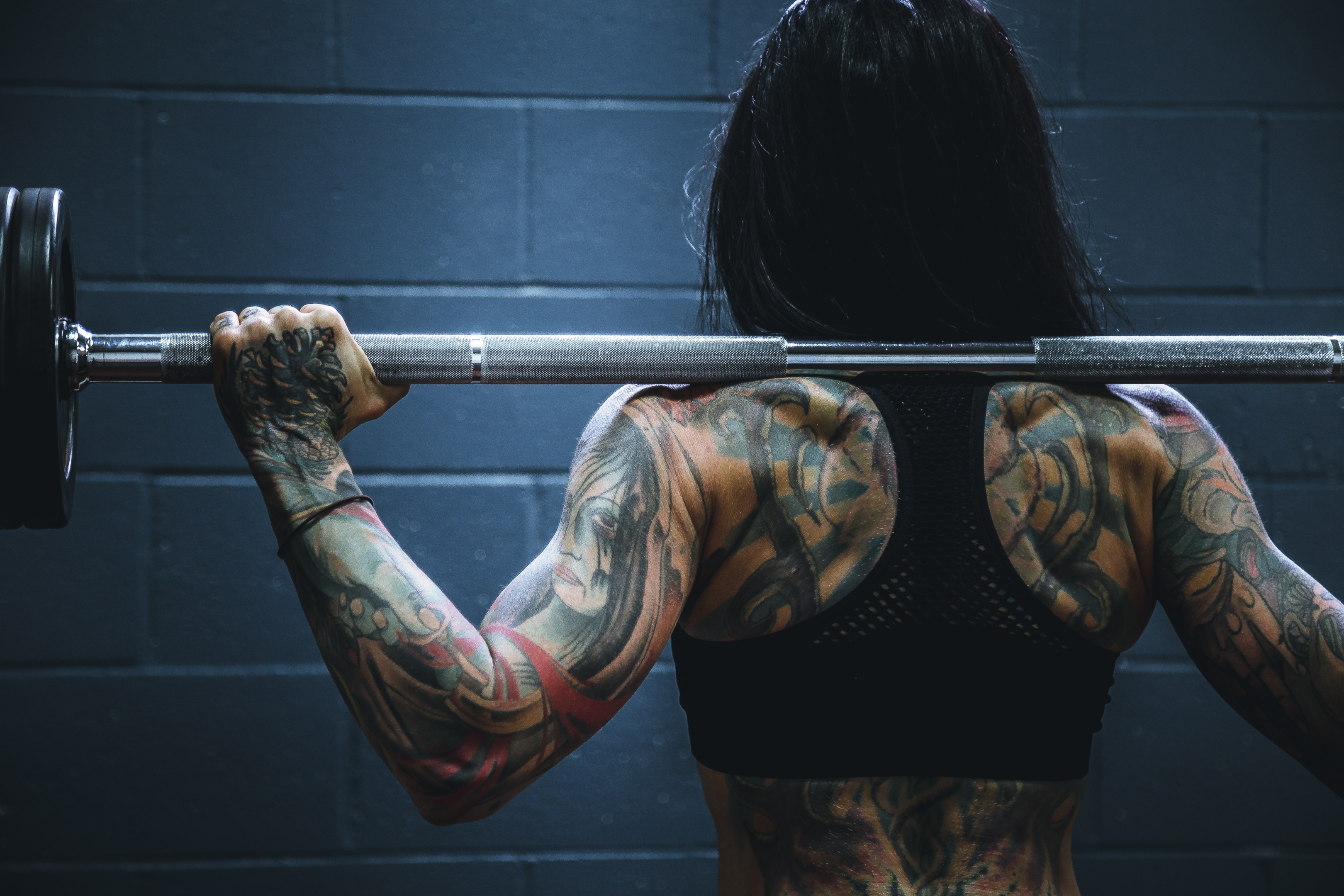 Mulher levantando peso. Foto de Alora Griffiths, Unsplash.