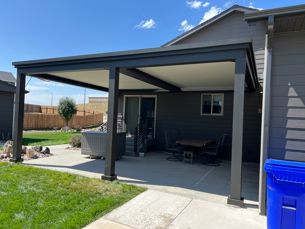 House attached black pergola installed over a patio.