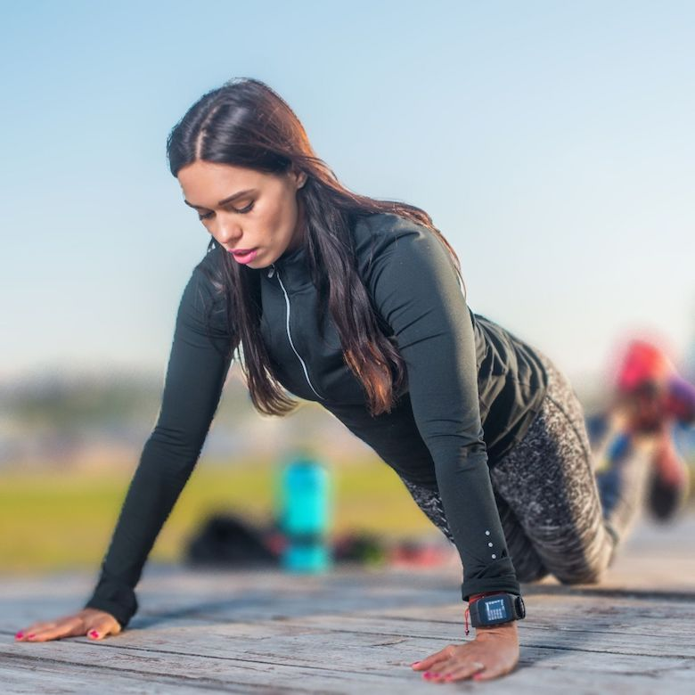 Young woman doing a push-up with knees bent outdoors
