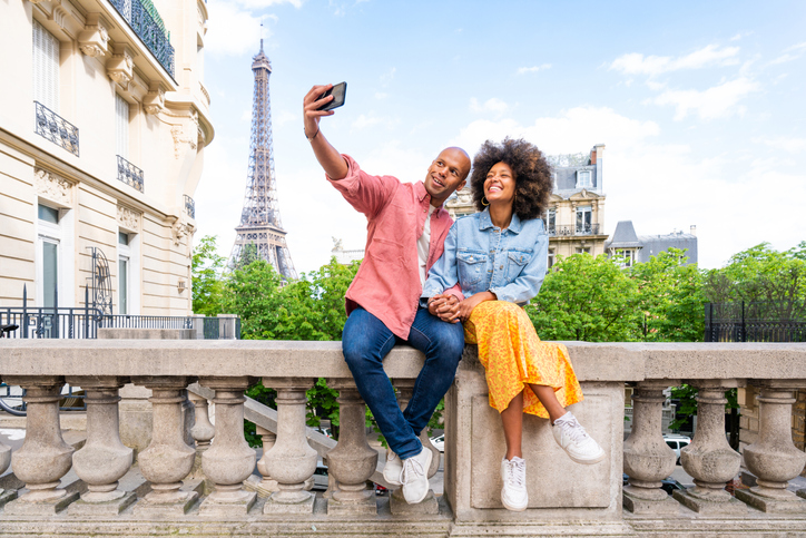 Adorable couple sitting on a concrete wall smiling for a selfie.