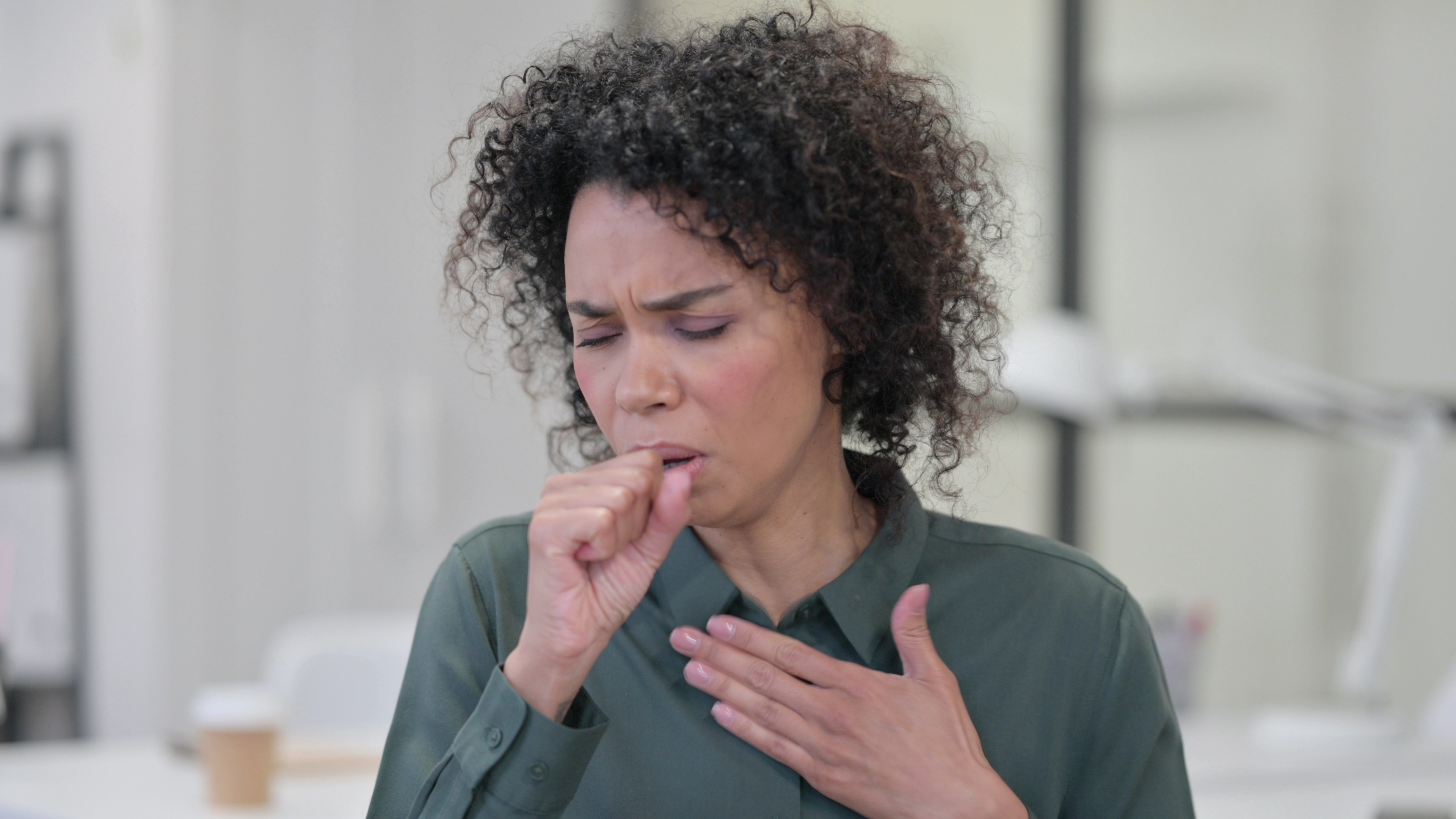An image of a woman with post nasal drip coughing into her hand.