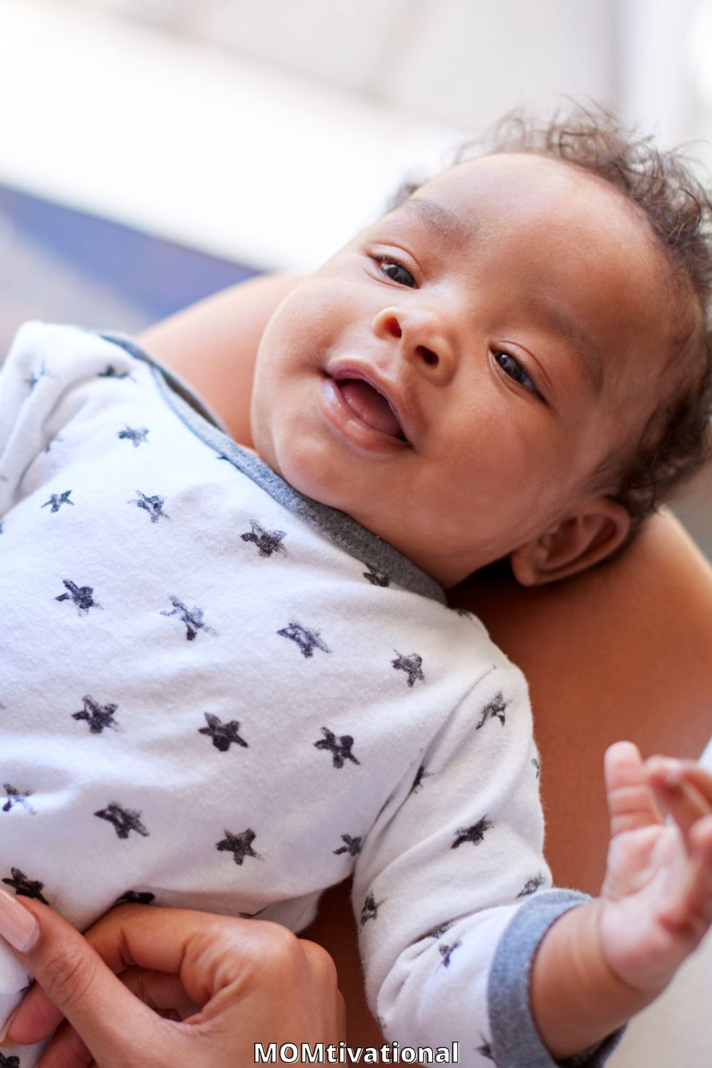 Cute baby boy smiling at cameraa on a persons lap